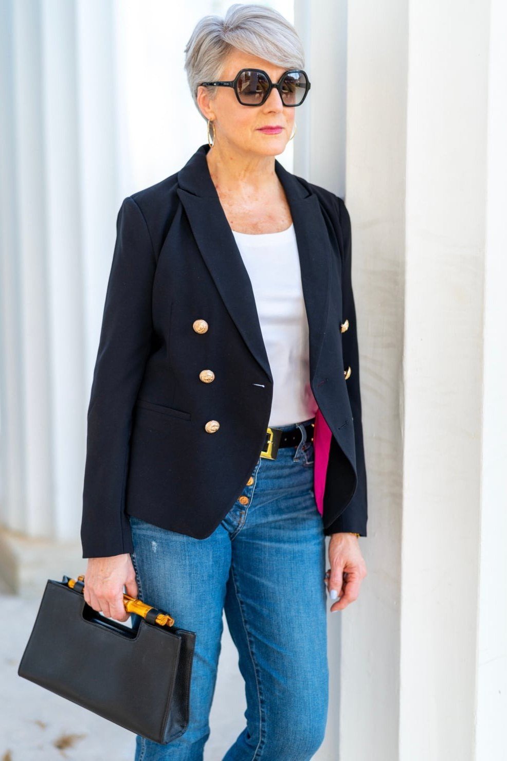 Effortlessly polished outfit for women over 50: A navy blazer over a white tee, medium-wash jeans, black leather tote; street