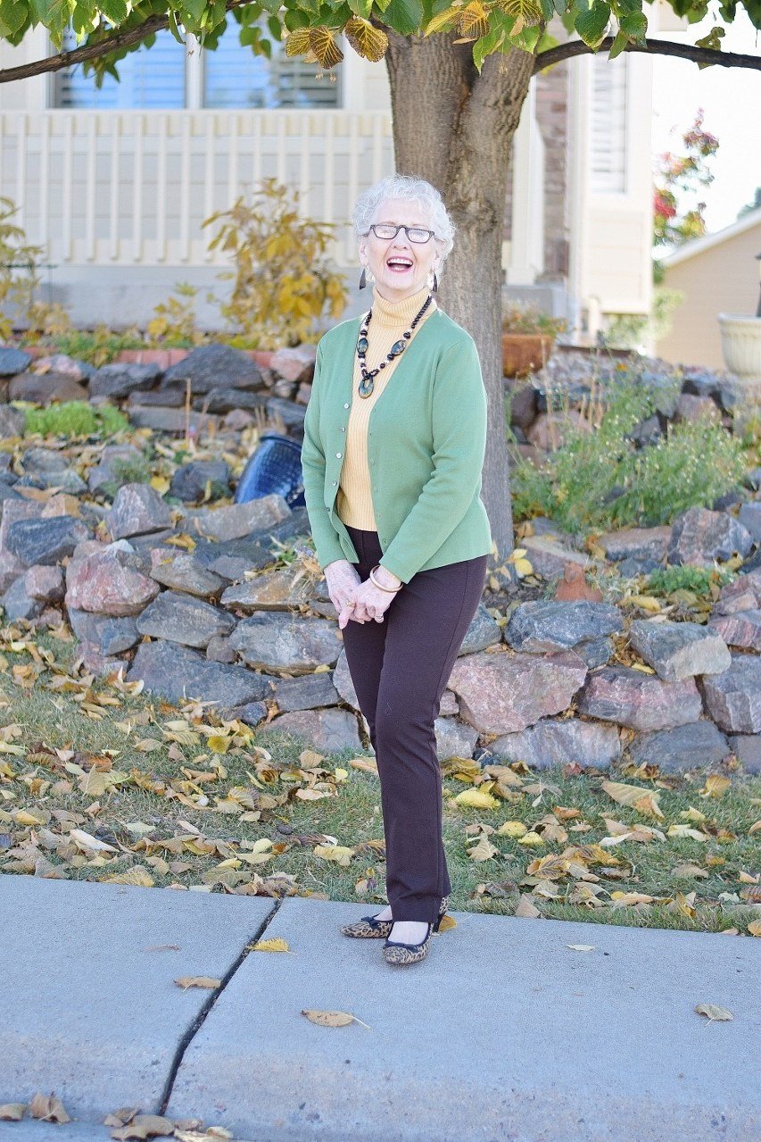 Older woman smiling in a mint green cardigan and black pants, fresh outfit idea for women over 70