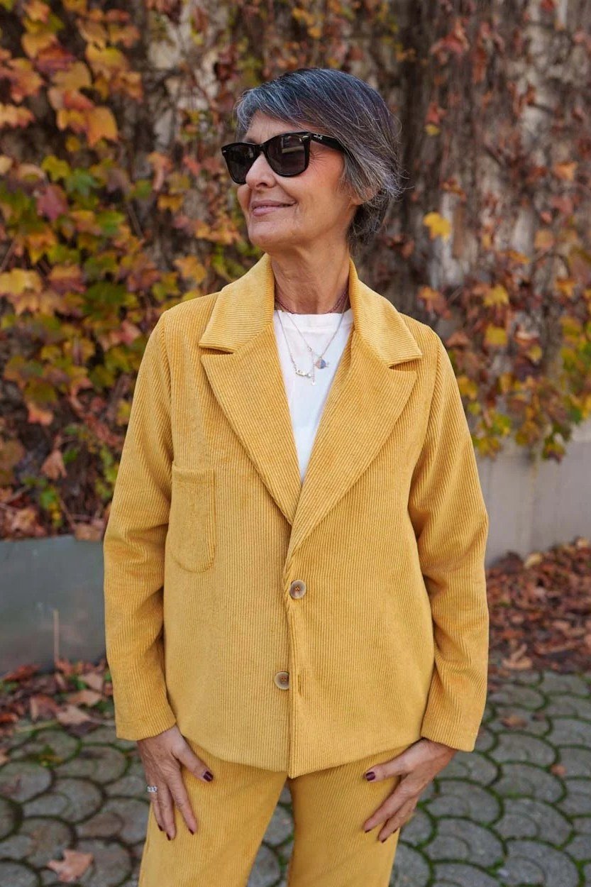 october outfits for women over 60: woman over 60 in mustard yellow blazer suit with white top by ivy wall