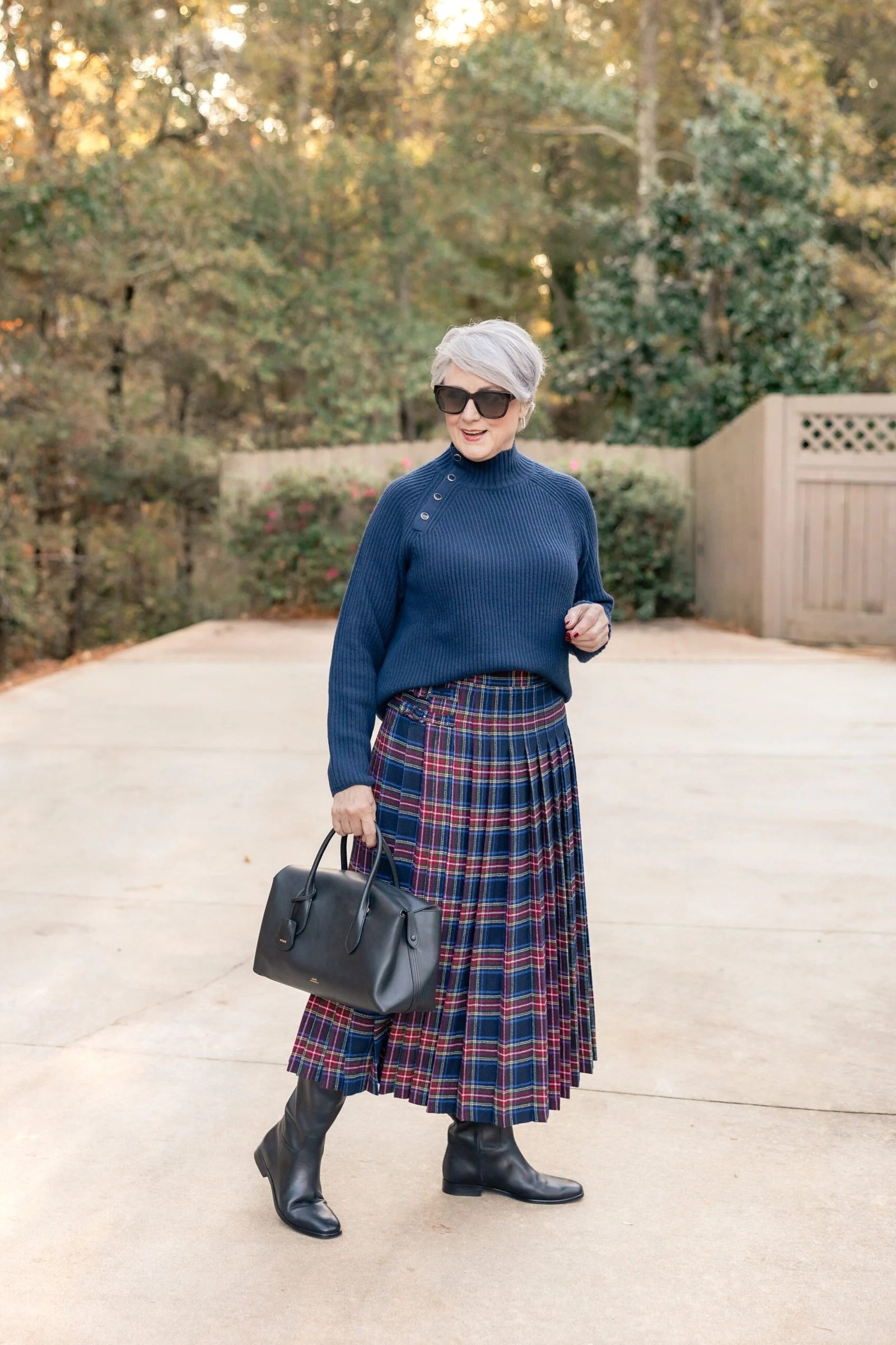 october outfits for women over 60: woman over 60 in navy sweater and red blue plaid midi skirt with black ankle boots