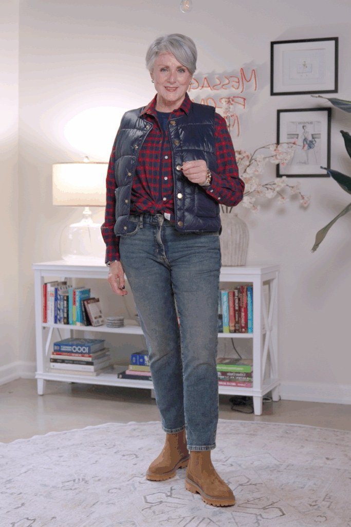 october outfits for women over 60: woman over 60 in red plaid shirt, navy quilted vest and jeans with tan boots indoors