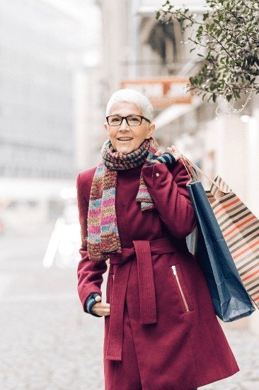 Trendy outfit for women over 70: burgundy coat + shopping bags