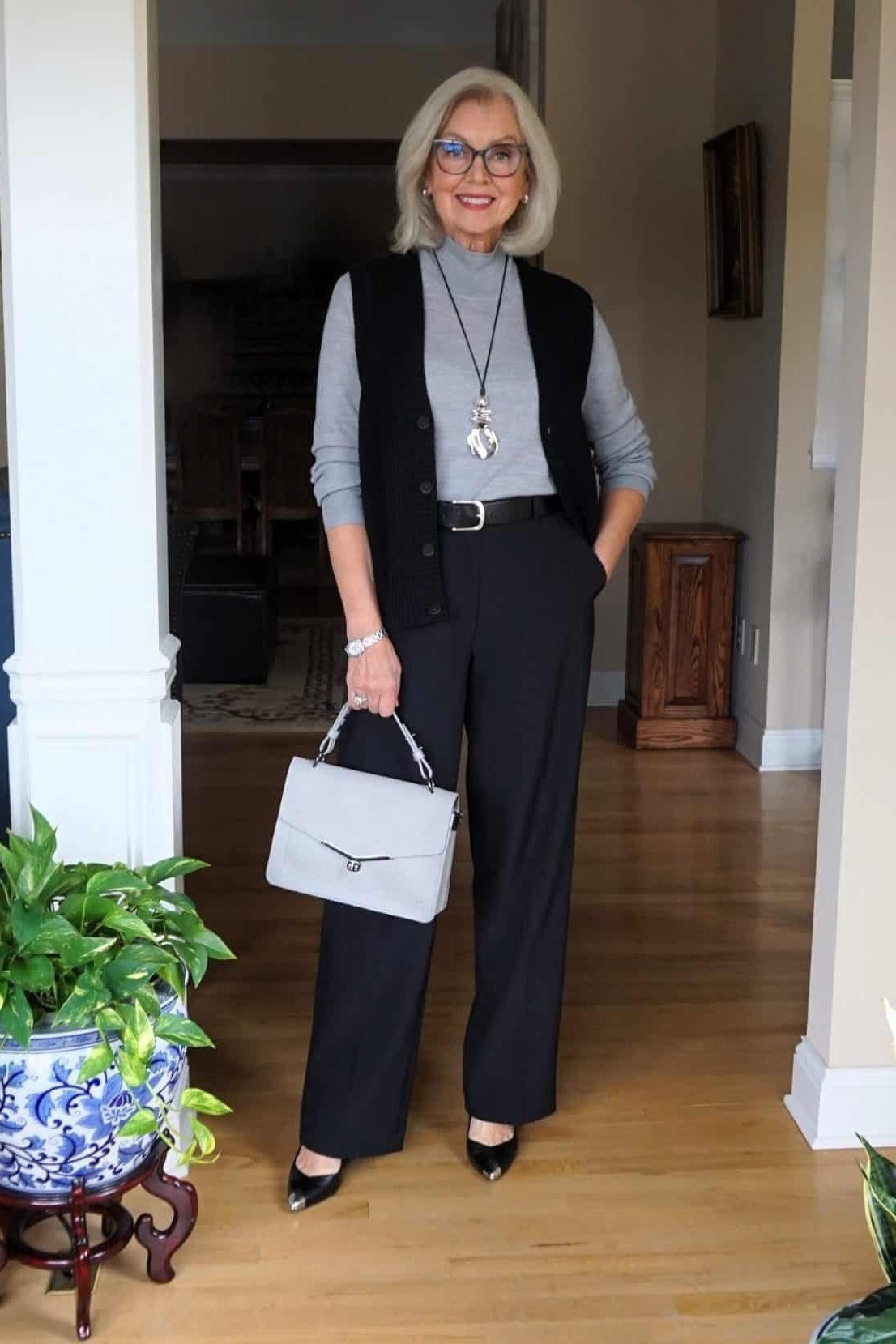 Trendy outfit for women over 70: black vest + blue shirt + navy wide-leg + white bag