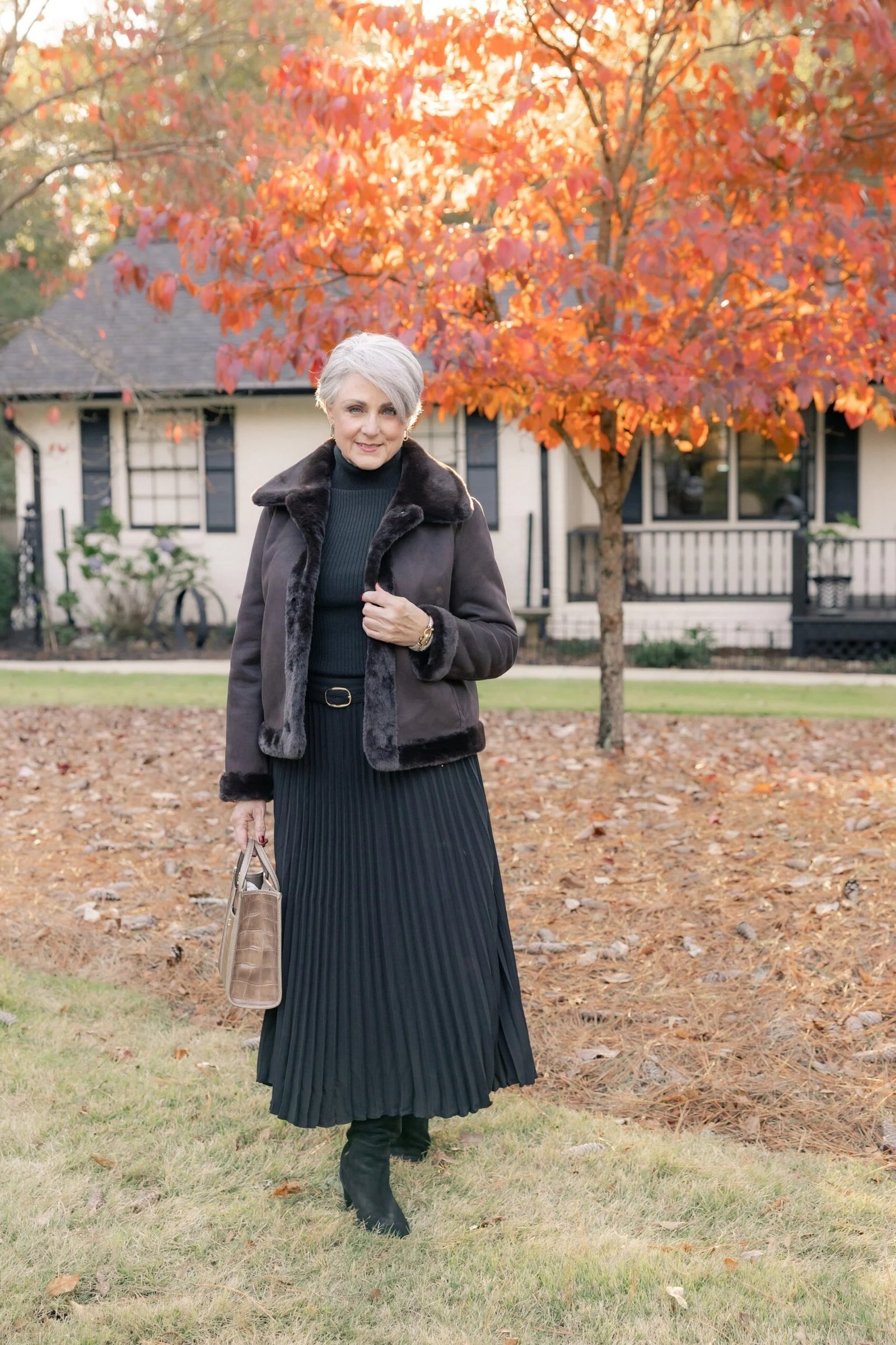 Trendy outfit for women over 70: black top + black pleated midi skirt, autumn
