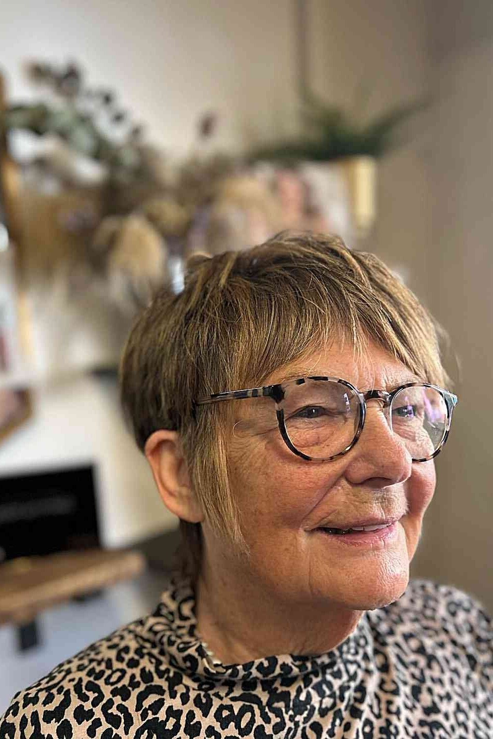 Brown pixie with glasses, older woman smiling - pixie haircut for women over 60