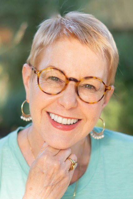 Blonde pixie with tortoise glasses, smiling outdoors - pixie haircut for women over 60