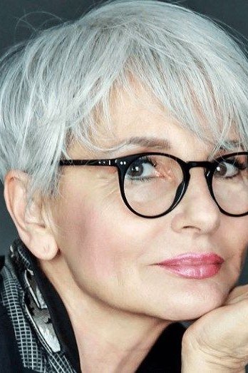 White pixie with black glasses, chin resting on hand - pixie haircut for women over 60