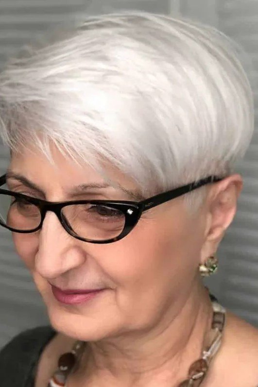White pixie with black glasses, smiling - pixie haircut for women over 60