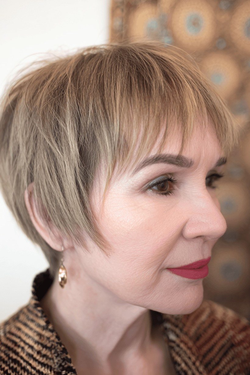 Honey-blonde pixie haircut with bangs side view