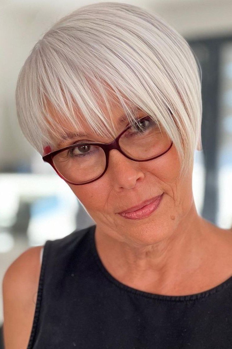 Sleek white pixie haircut with polished finish and red glasses