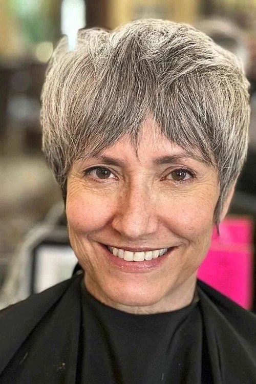 Salt and pepper pixie haircut with wispy fringe for women over 60