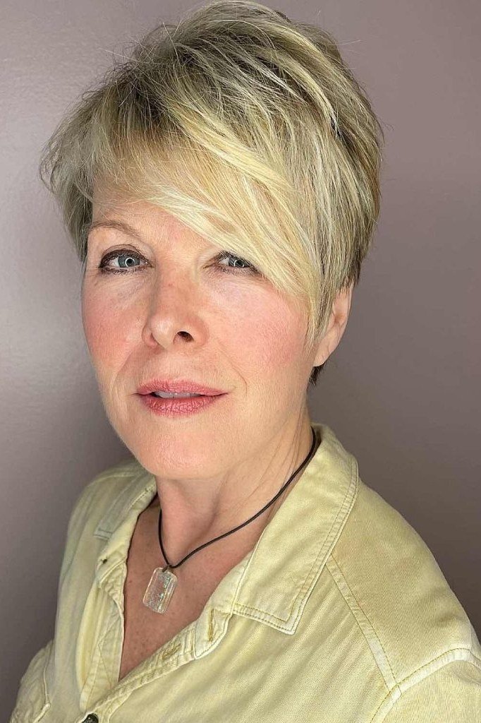 Honey blonde pixie haircut with side swept bangs for women over 60