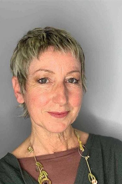 Grey pixie haircut with green tint and straight fringe for women over 60
