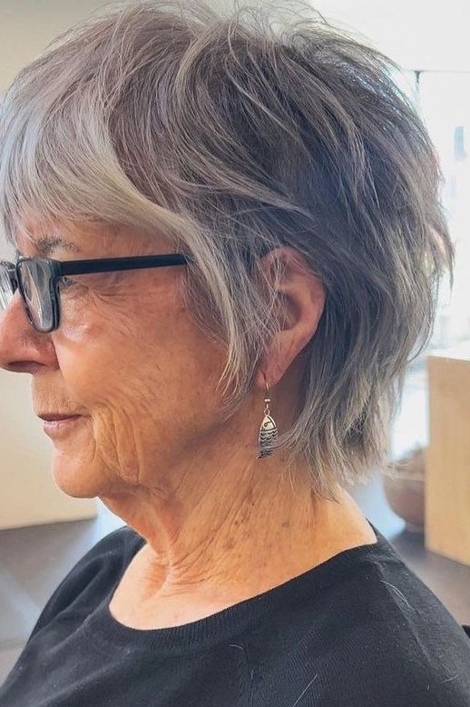 Silver grey pixie haircut with soft bangs and glasses for older women