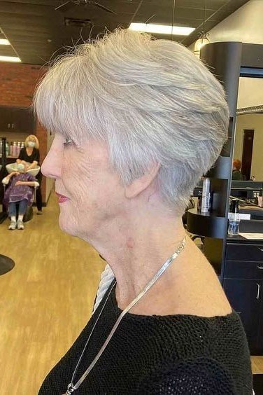 White pixie haircut with precision bangs at the salon for women over 60, profile view