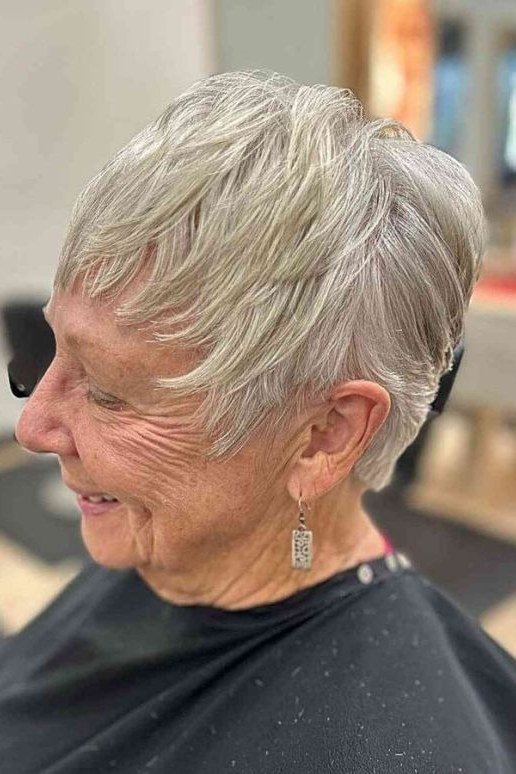 Grey pixie haircut with tapered nape and soft bangs for women over 60, profile view