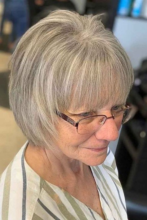 Bright white pixie haircut with bangs and glasses for older women