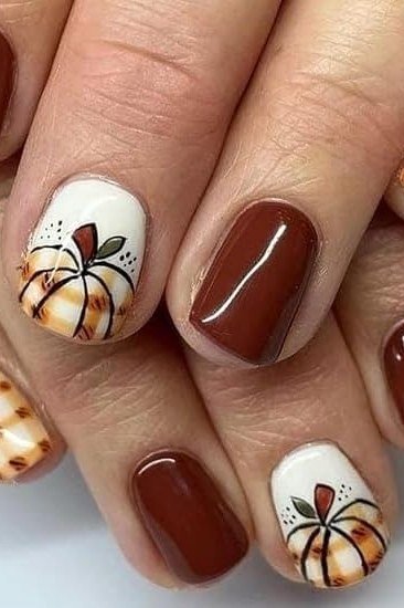 Cocoa brown nails with pumpkin art over plaid background