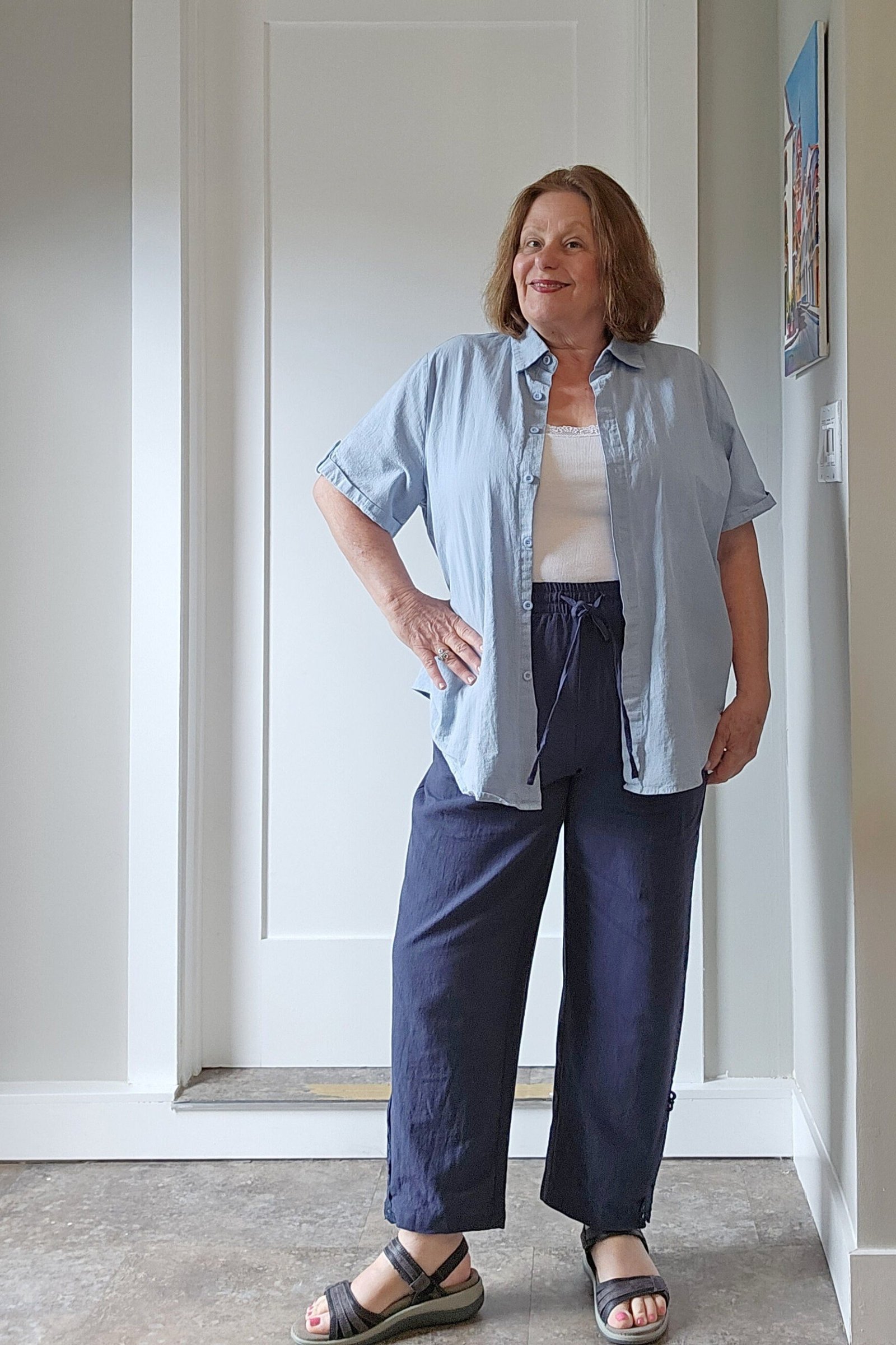 curvy woman over 60 wearing chambray shirt with navy wide-leg trousers and sandals