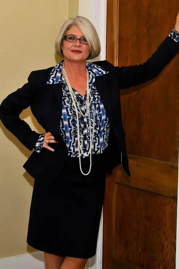 plus-size woman over 60 wearing black blazer with blue patterned blouse and pencil skirt