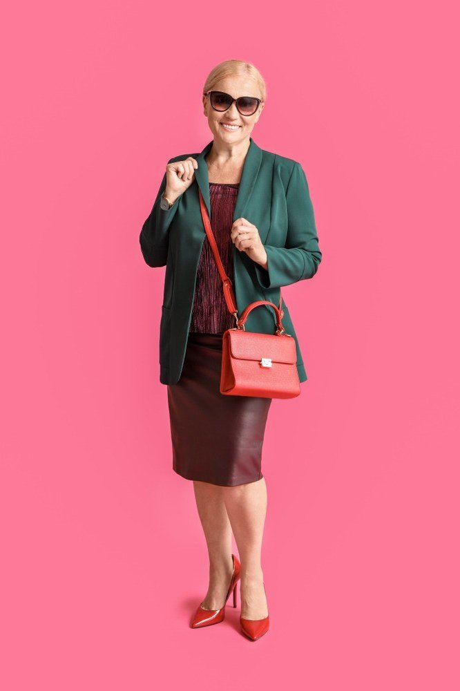 plus-size woman over 60 wearing emerald blazer with burgundy top and pencil skirt with red heels