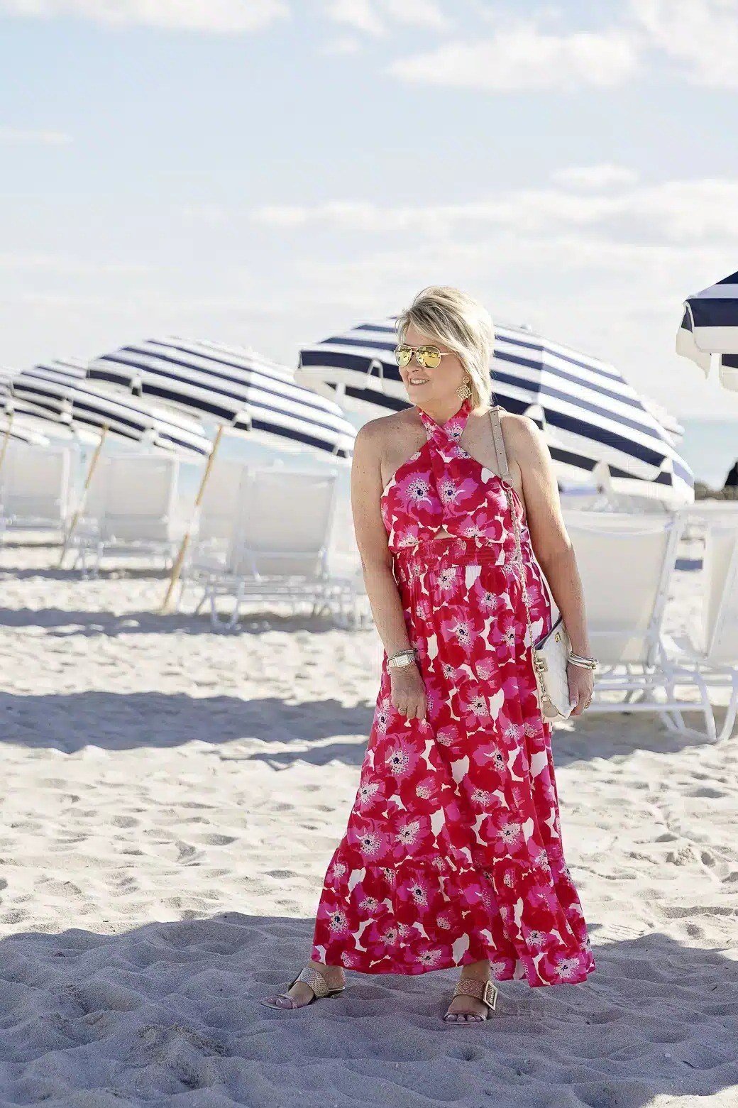 plus-size woman over 60 wearing red floral maxi sundress with straw hat on beach boardwalk