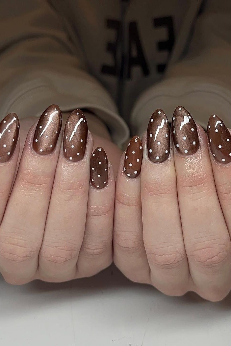 Brown and champagne cat-eye nails with white polka dots on both hands, fall nail design