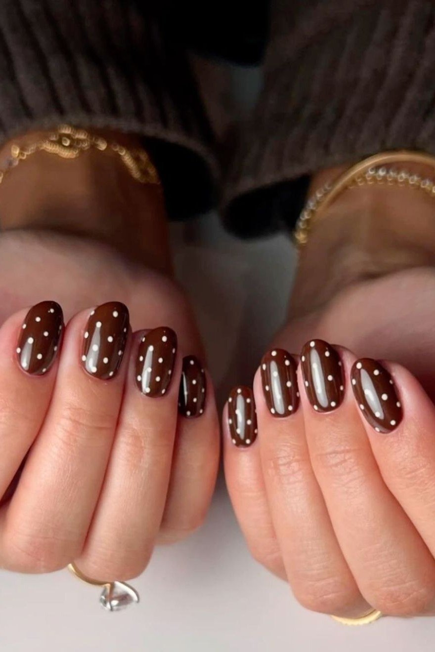 Deep burgundy short nails with white polka dots on both hands, fall nail design for older women