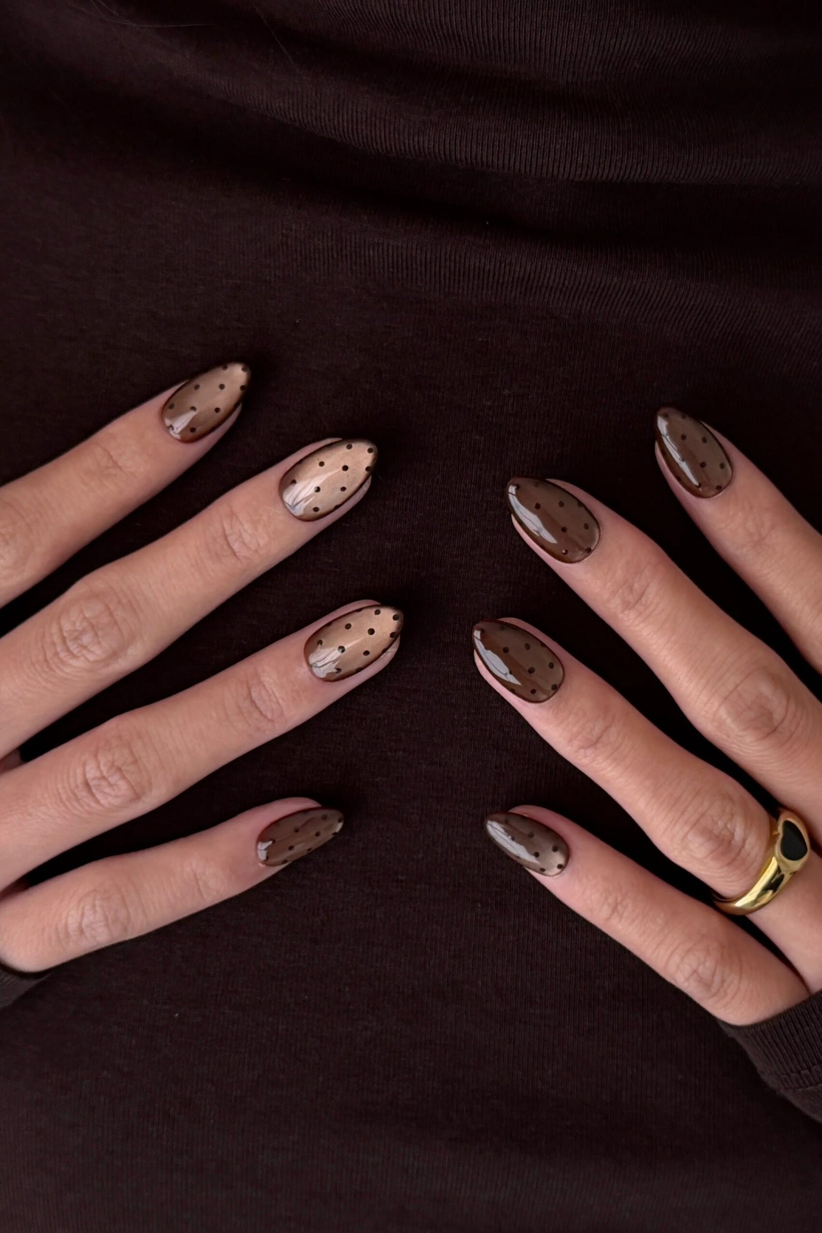 Taupe cat-eye almond nails with white polka dot accents and gold rings