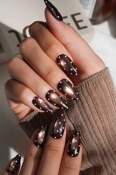 Dark chocolate cat-eye almond nails with white polka dots and a brown knit sweater