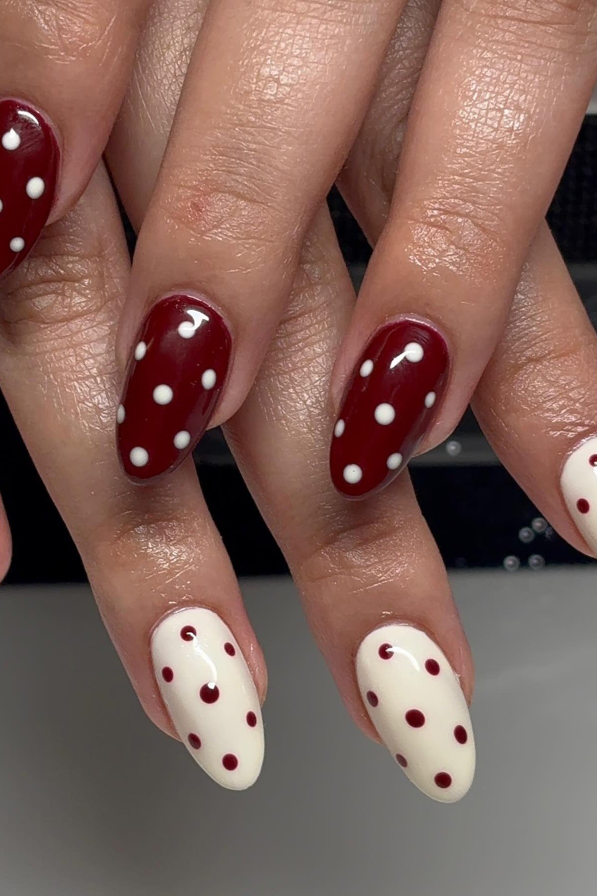 Glossy red almond nails with white polka dots, classic fall nail art