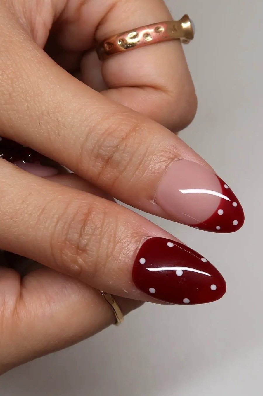 Red almond nails with white polka dot French tips close up