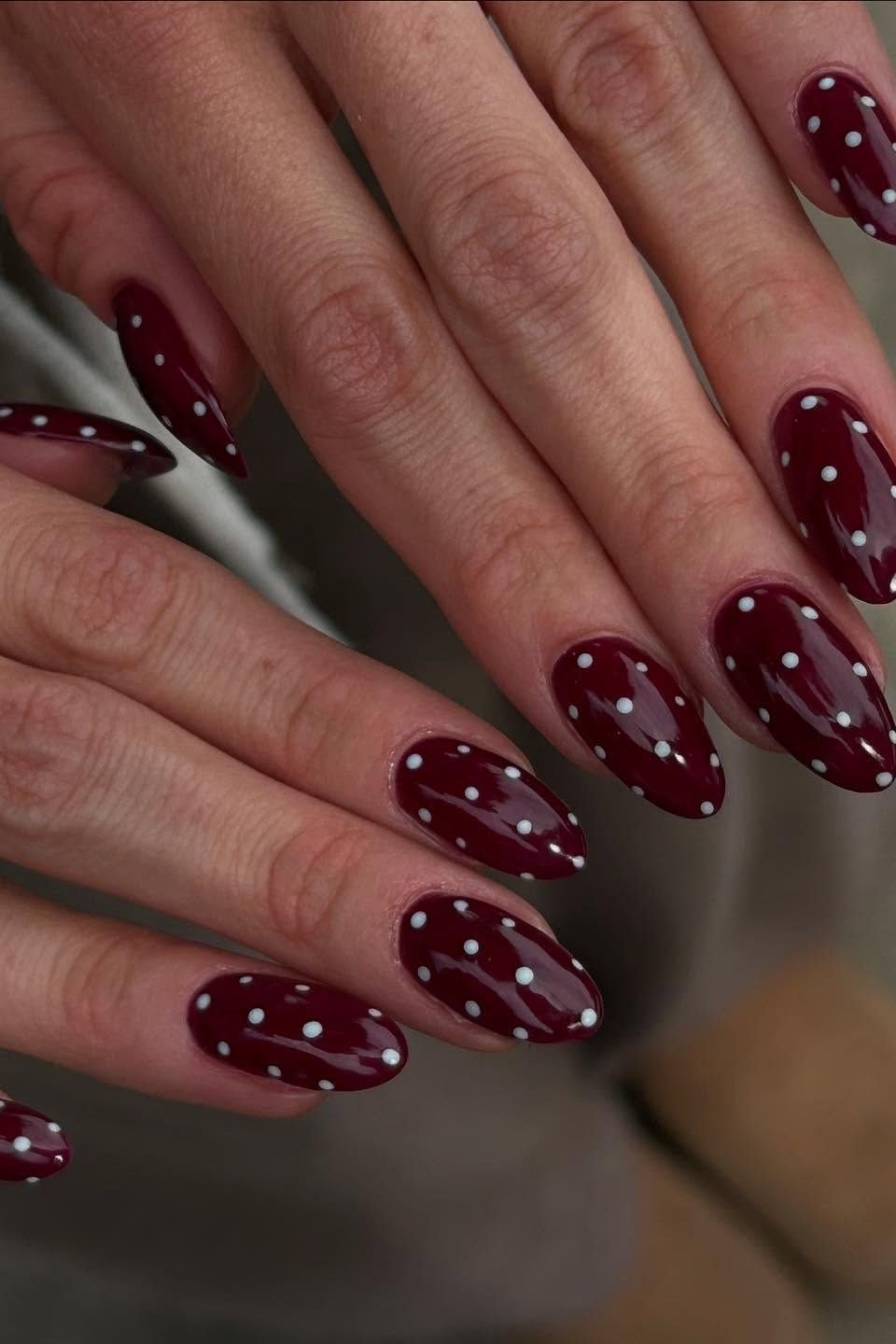 Oxblood almond nails with white polka dots on both hands, elegant fall nails