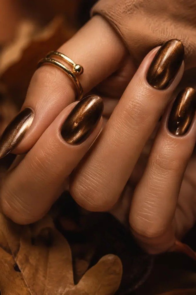 Copper cat-eye almond nails with a gold ring and brown sleeve, fall cat-eye nail art