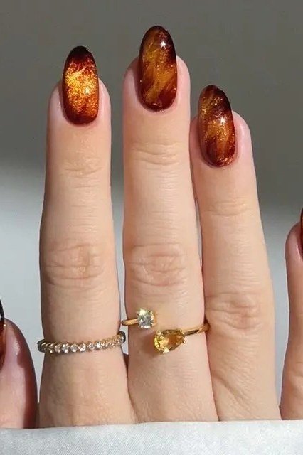 Copper cat-eye almond nails with stacked gold rings, luxe fall nail design