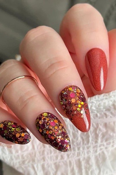 Terracotta glitter almond nails with white polka dots and a gold ring