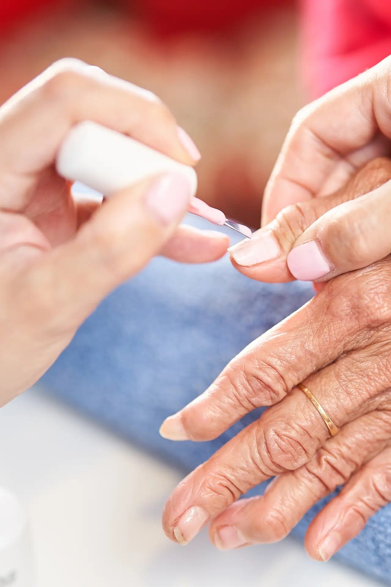 Glue being applied to an elderly woman's natural nail before press-on