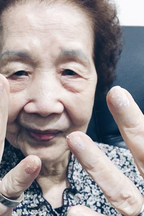 Smiling senior woman proudly showing off her fresh red nails
