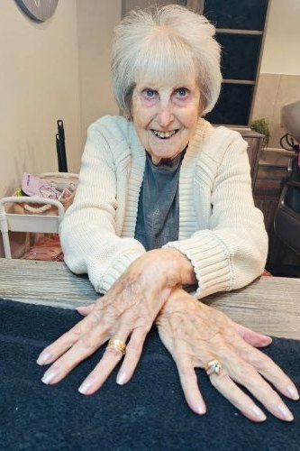 White-haired elderly woman showing her natural short nails
