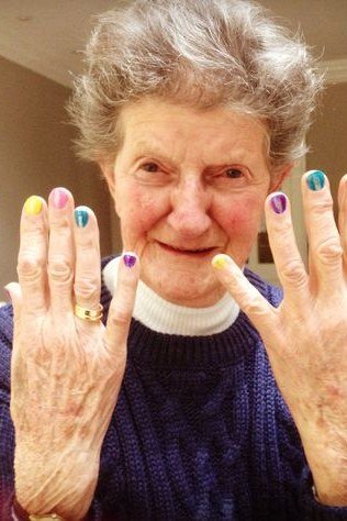 Cheerful elderly woman showing multicolor pastel press-on nails