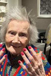 Elderly woman smiling with colorful confetti-style nails