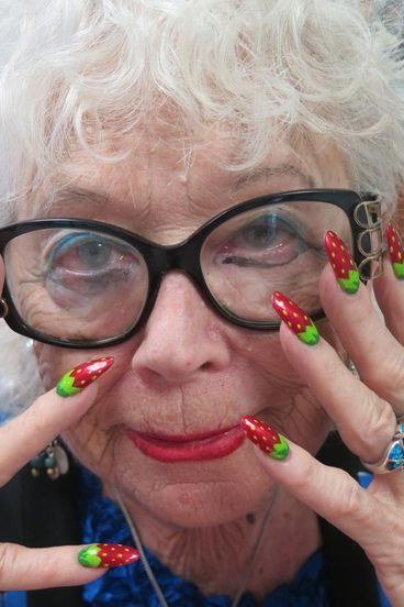 Playful elderly woman with glasses and strawberry nail art