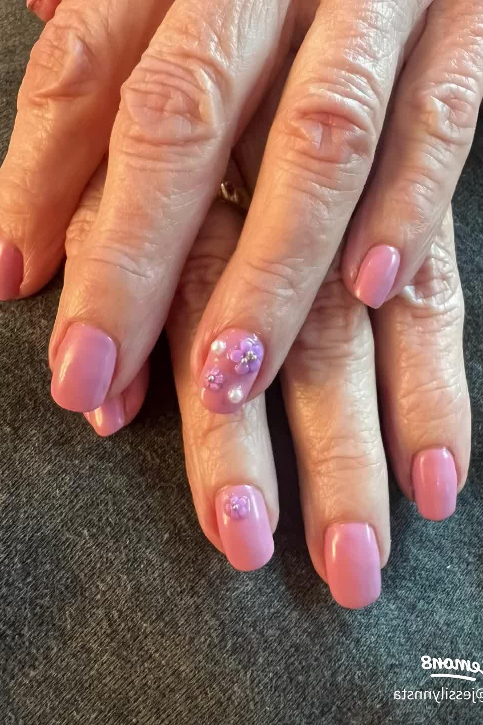 Mature crossed hands with pink nails and a glitter accent