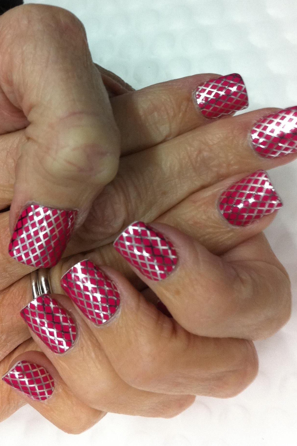 Hands wearing red houndstooth-patterned press-on nails