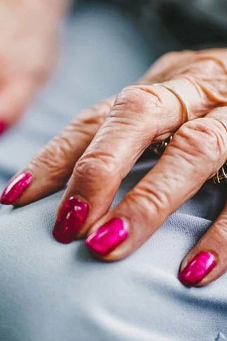 Elderly hands with pink-to-red ombre press-on nails