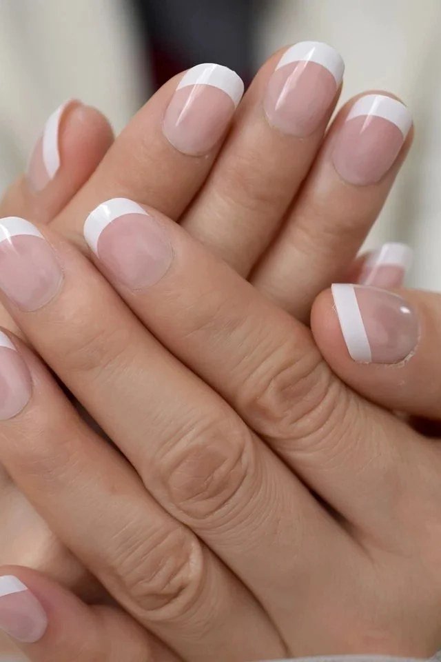 Mature crossed hands with classic French-tip press-ons