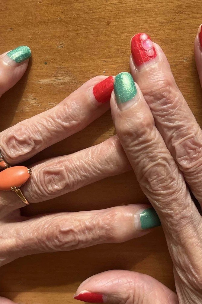 Mature hands with multicolor short press-on nails (red, green, orange)