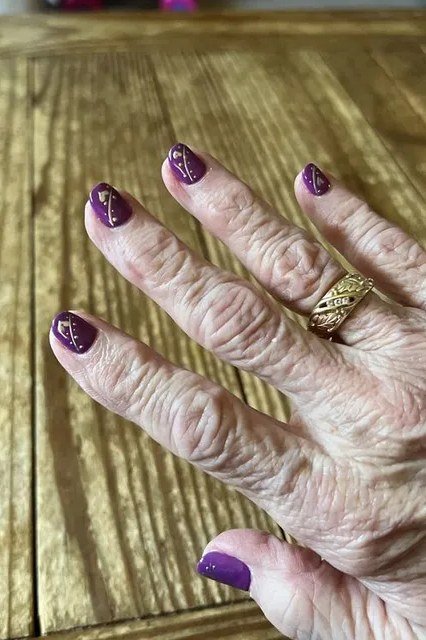 Mature hand with dark purple glitter nails