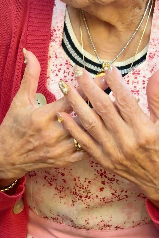 Elderly hands with gold-tipped press-on nails