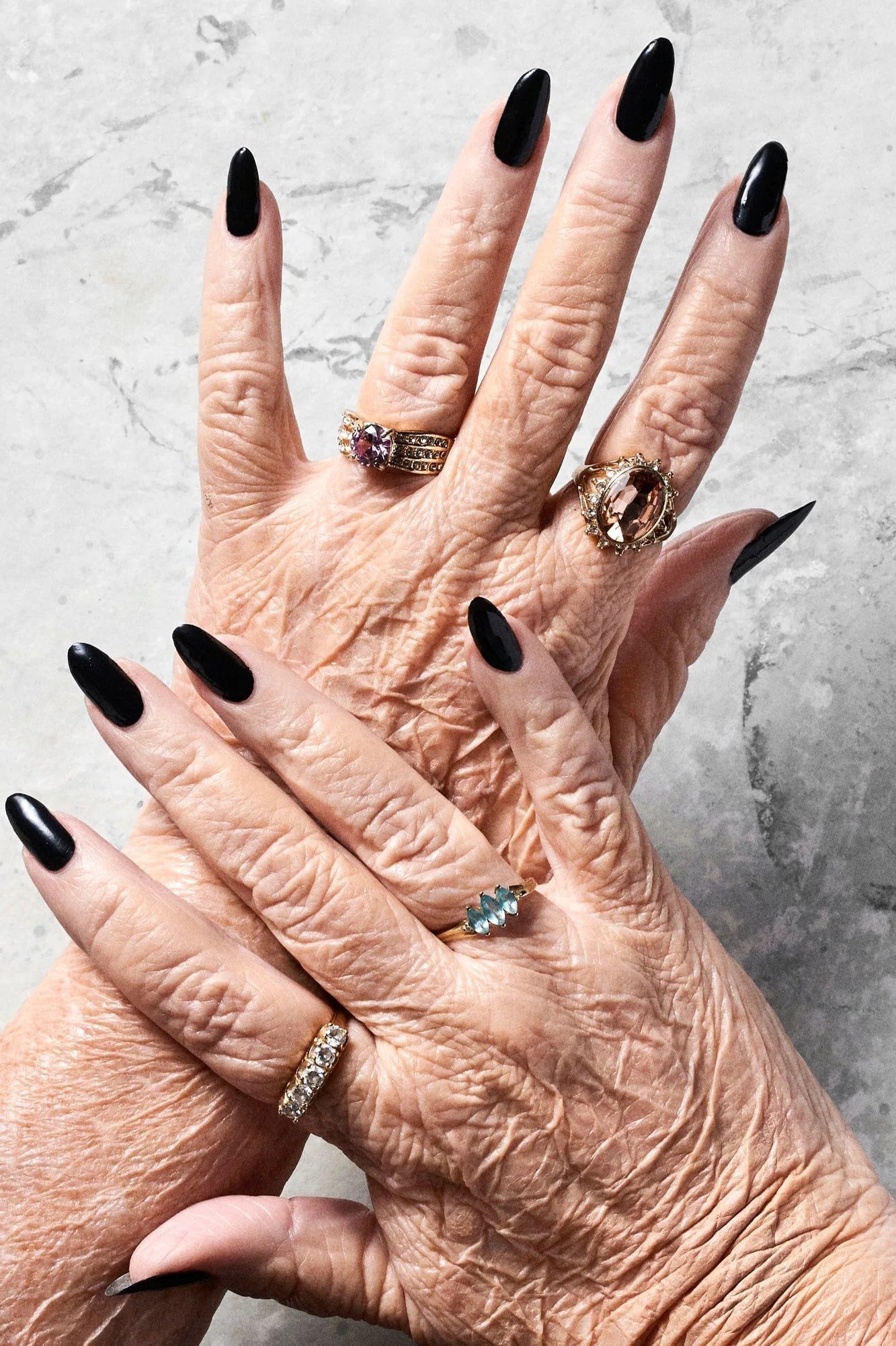 Elderly crossed hands with long black press-on nails